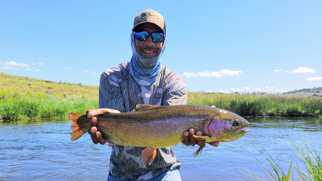A fly fisherman holding a huge rainbow trout from Hot Creek.