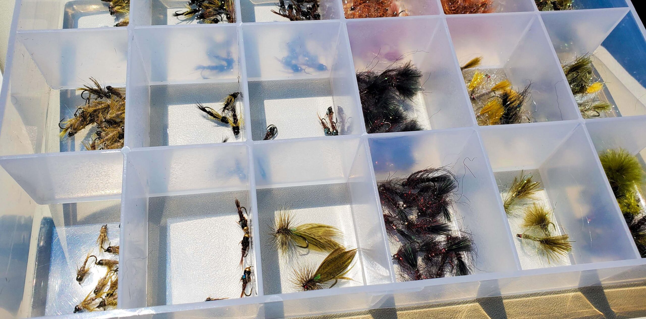 A clear fly box from an Eastern Sierra Fishing Guide full of fly fishing flies.
