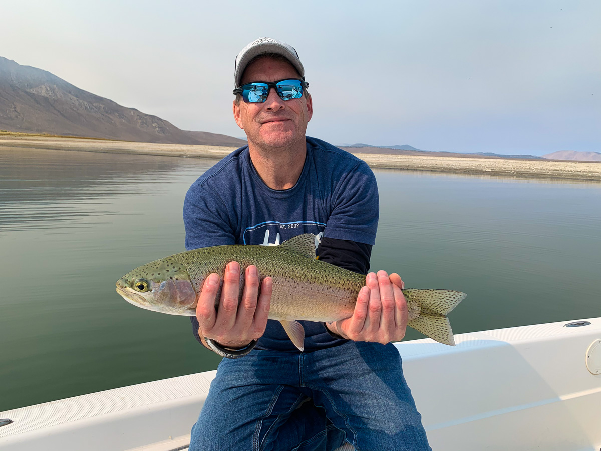 A fly fisherman holding a rainbow trout from Crowley Lake.
