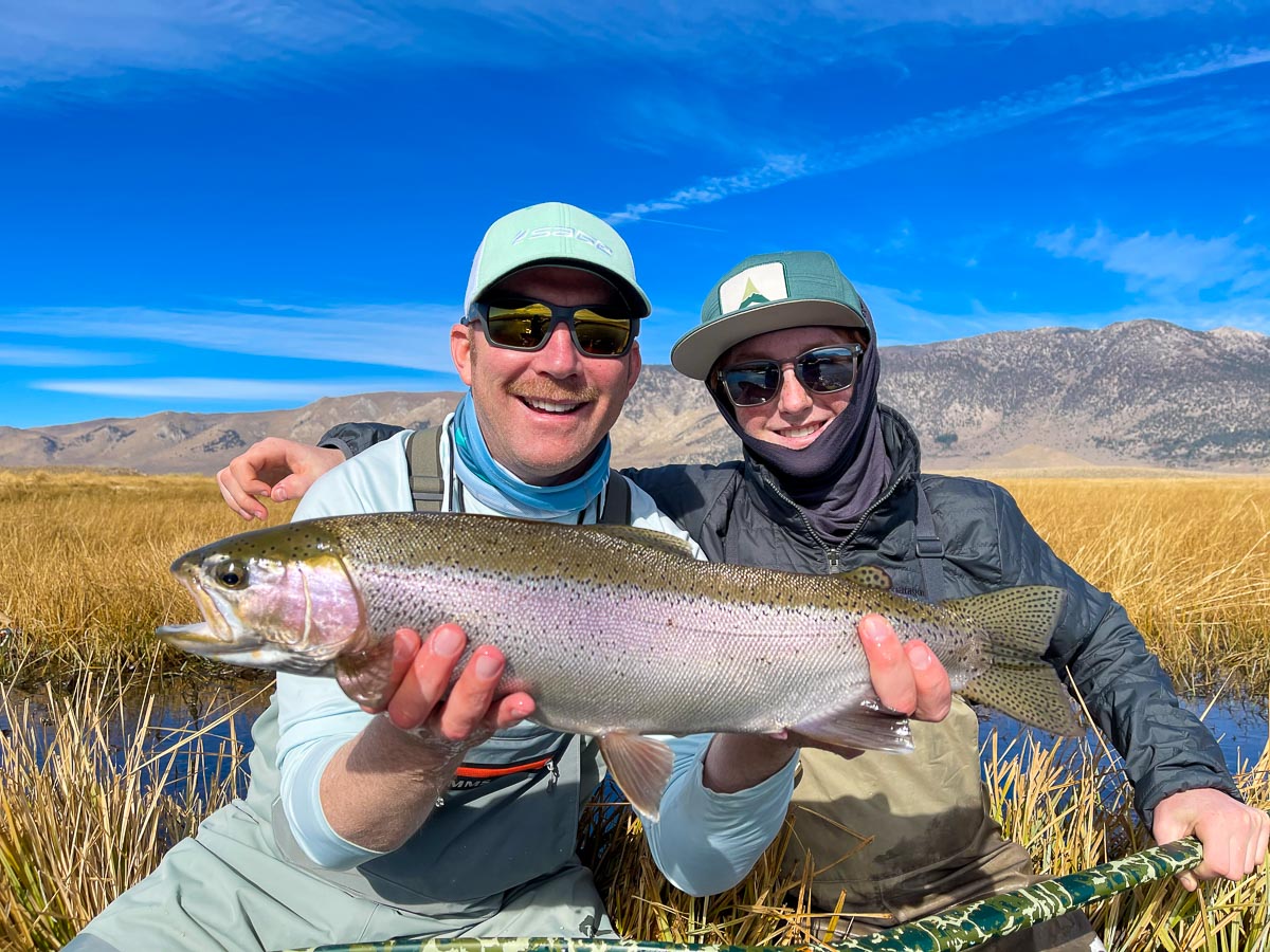 A fly fisherman along with his son displaying a giant rainbow trout from the Upper Owens River.