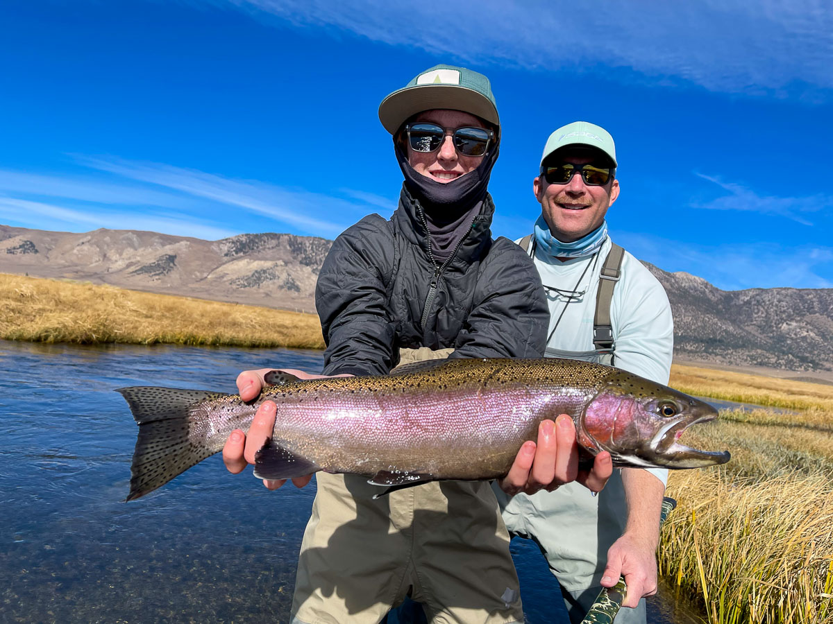 A fly fisherman along with his dad displaying a giant rainbow trout from the Upper Owens River.