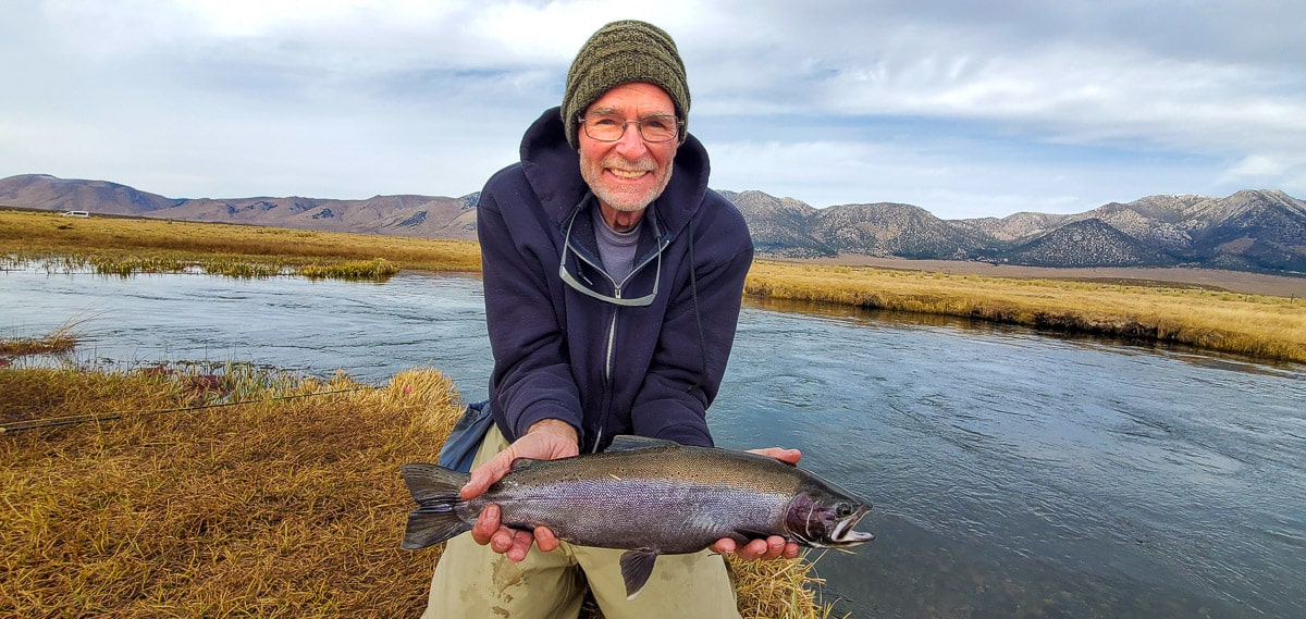 A fly fisherman holding a rainbow trout during the fall spawn from the Upper Owens River.