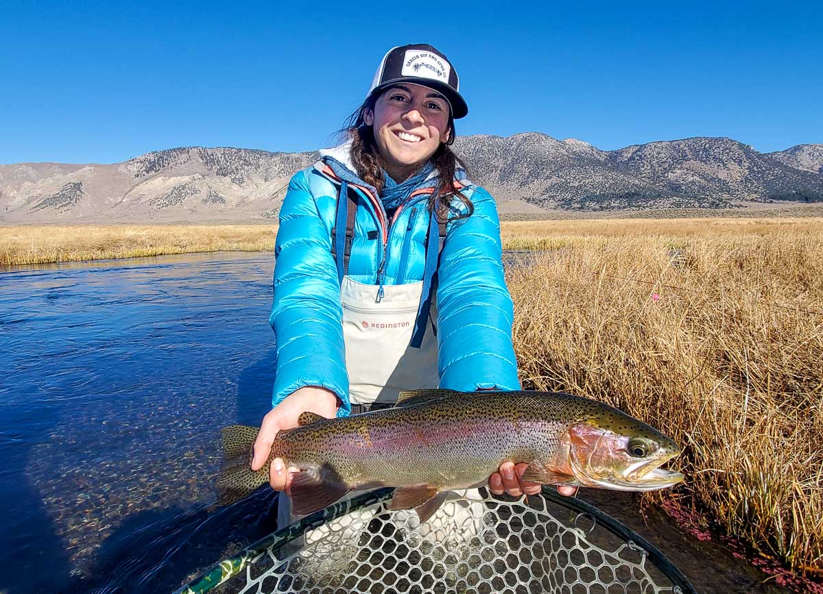 A lady fly fisherman holding a rainbow trout during the fall spawn from the Upper Owens River.