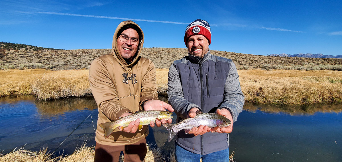 A pair of fly fisherman holding a rainbow trout and a brown trout from Hot Creek.