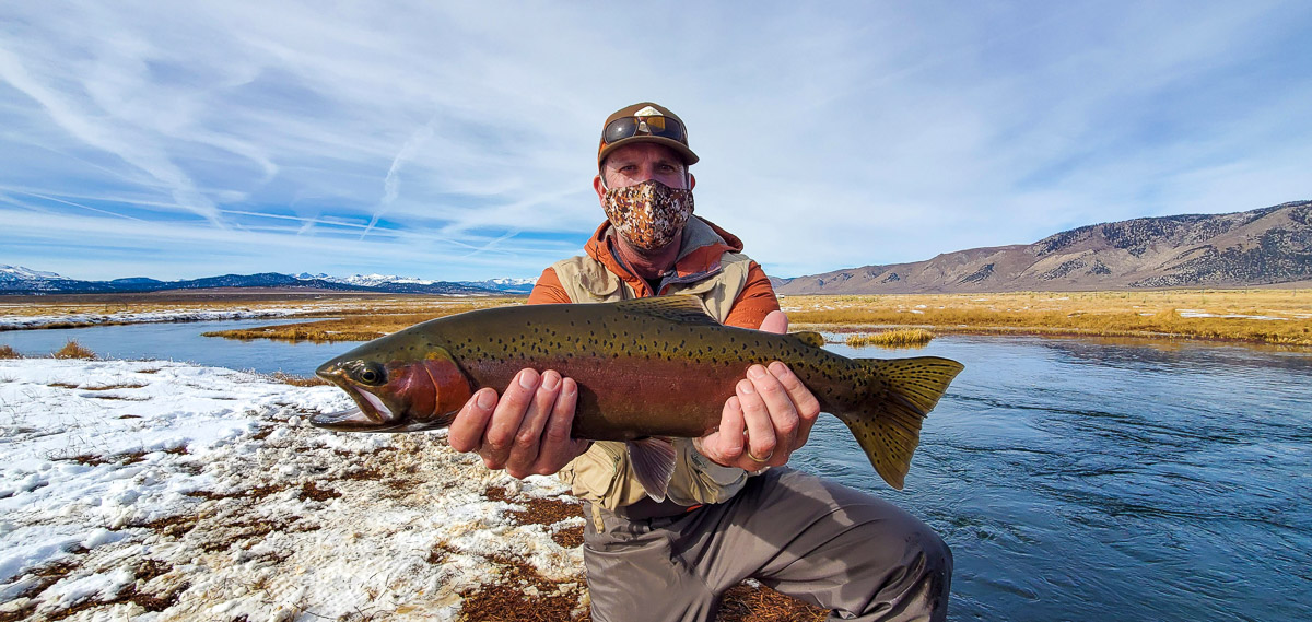 A young fly fisherman holding a rainbow trout during the fall spawn from the Upper Owens River.