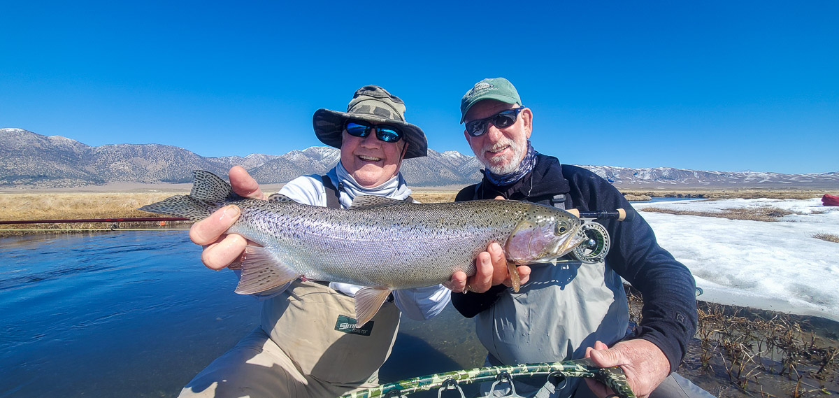 A pair of fly fisherman holding a rainbow trout in spawning colors from the Upper Owens River.