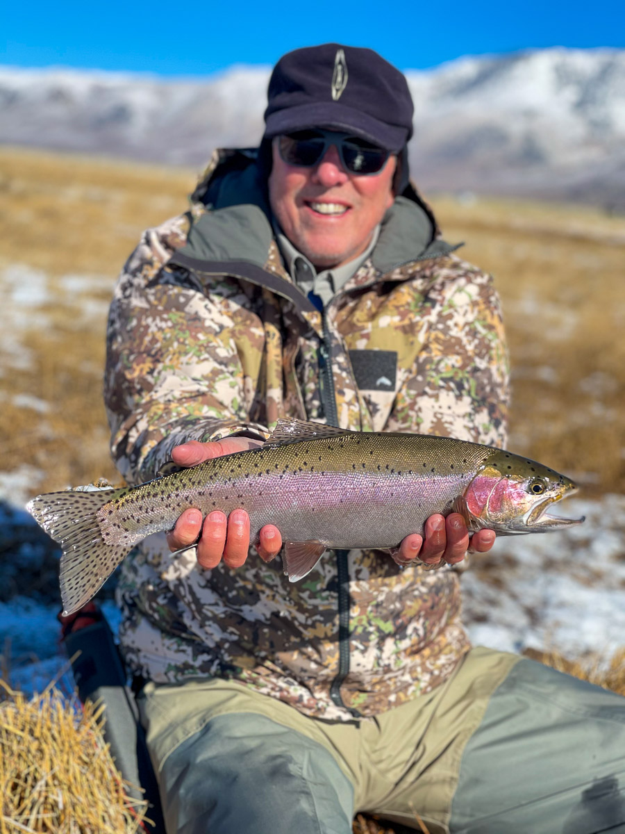 A fly fisherman holding a rainbow trout in spawning colors from the Upper Owens River..
