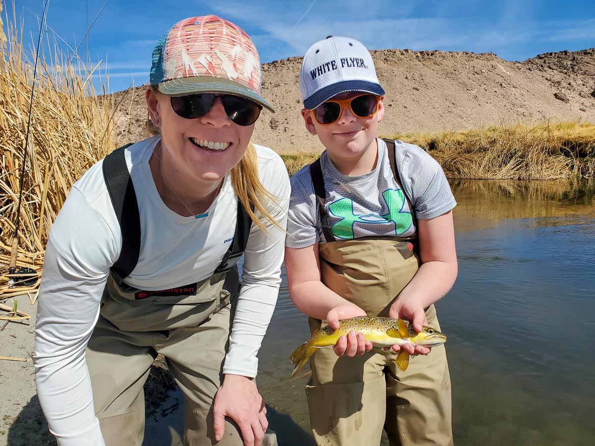 A fly fisherwoman and a young boy holding a brown trout from the Lower Owens River.