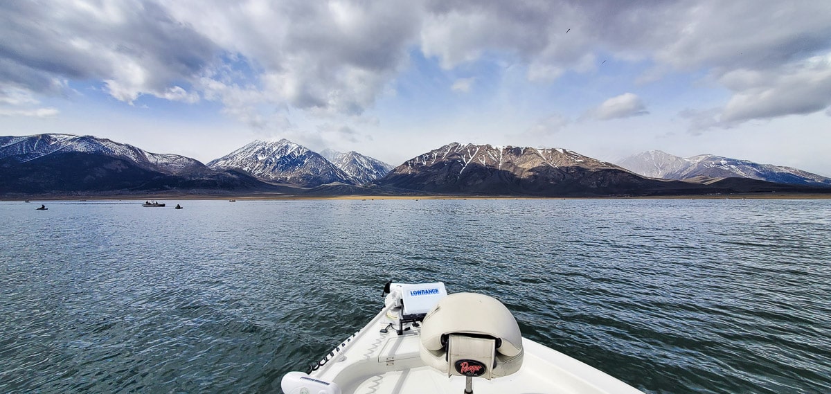 Looking out to the horizon from a boat on a lake in the eastern sierra with snowy mountains in the distance.