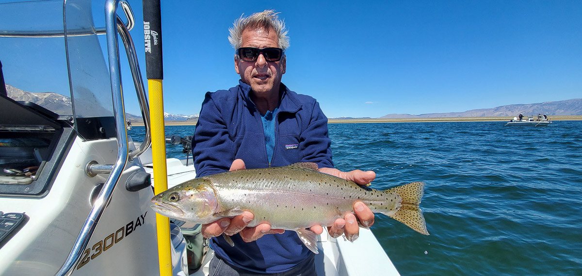 A smiling angler holding a cutthroat trout from Crowley Lake.