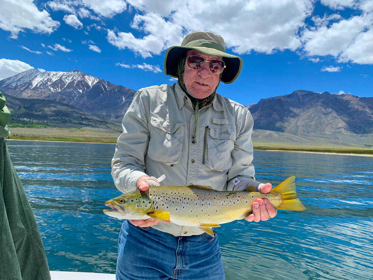 A man holding a large brown trout on a lake.