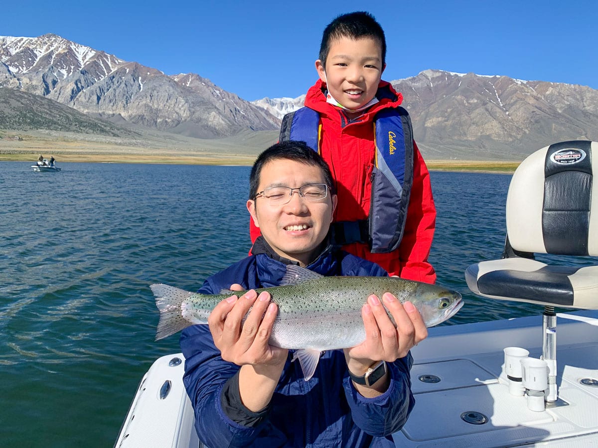 A father and son fly fishing team with a large rainbow trout from a mountain lake in the eastern sierra.