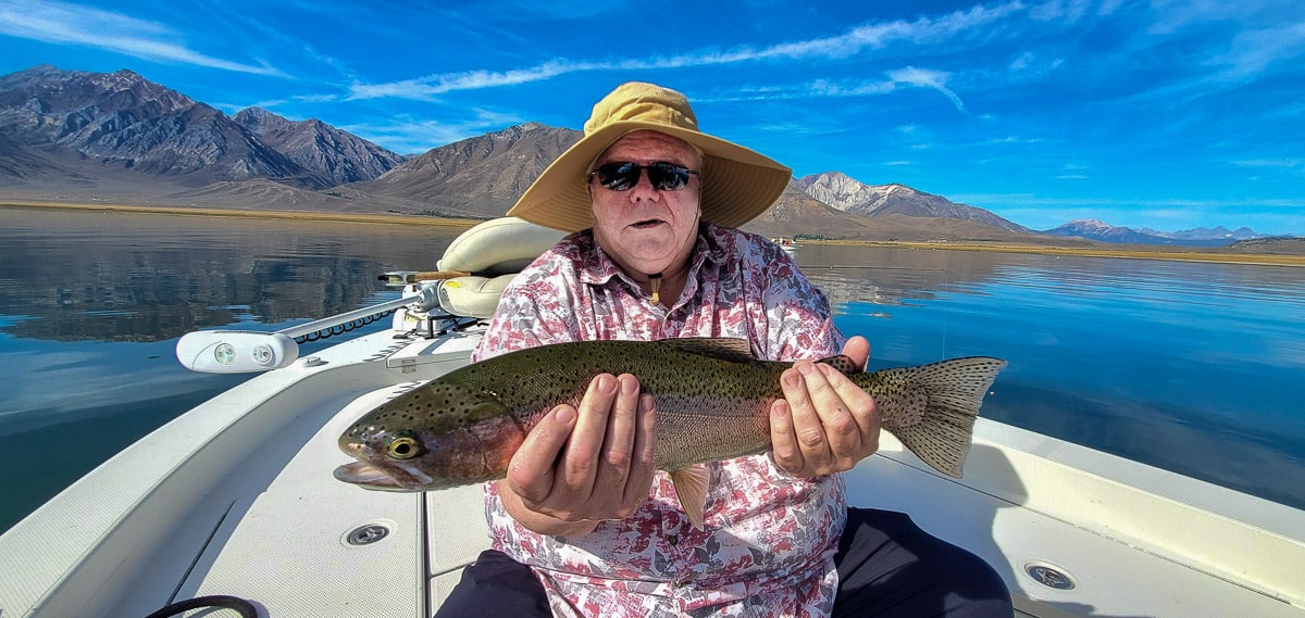 A fly fisherman holding a rainbow trout from Crowley Lake.