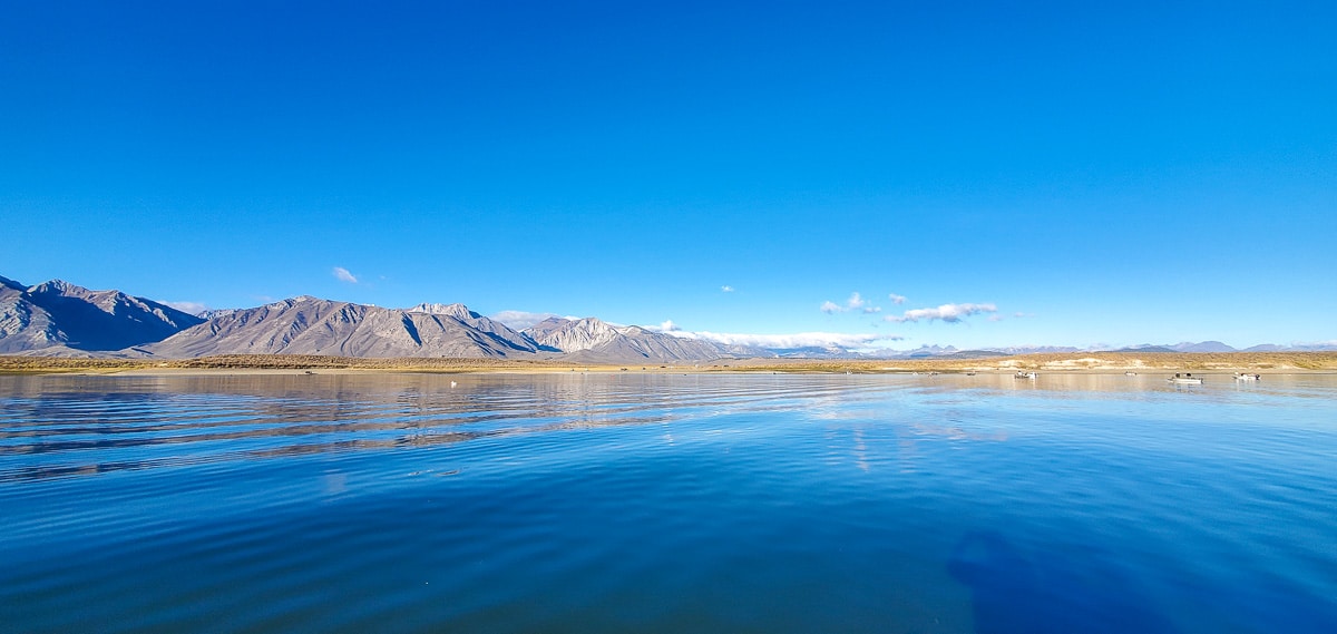 A mountain lake with mountains in the background and low clouds above them.