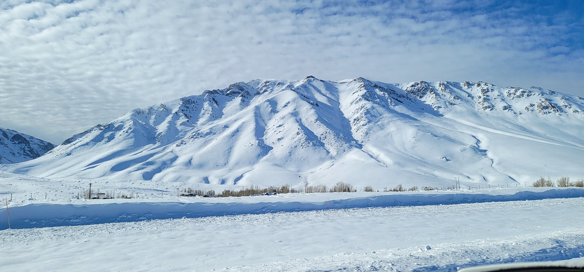 A snow covered mountain with a mackerel sky cloud formation.