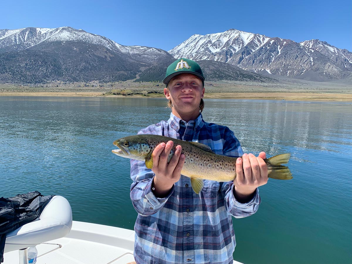 A fly fisherman in a river holding a large rainbow trout..