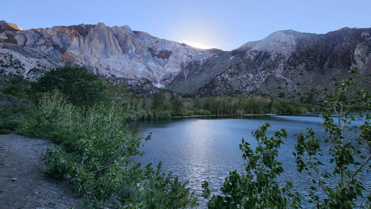 A lake in the eastern sierra with the sun setting behind the mountains.