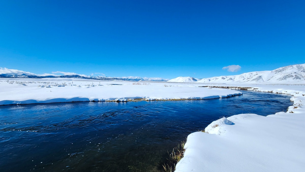 A river running through snow covered banks in the winter.