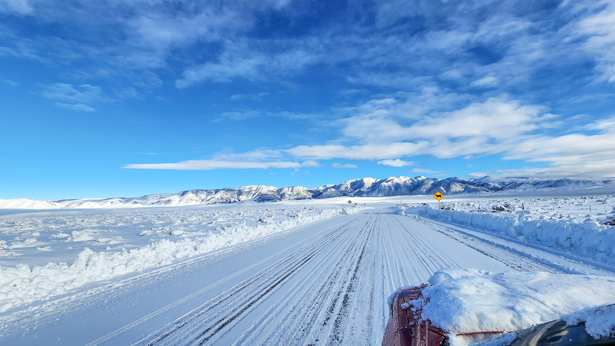 A snow covered road and landscape in the mountains.