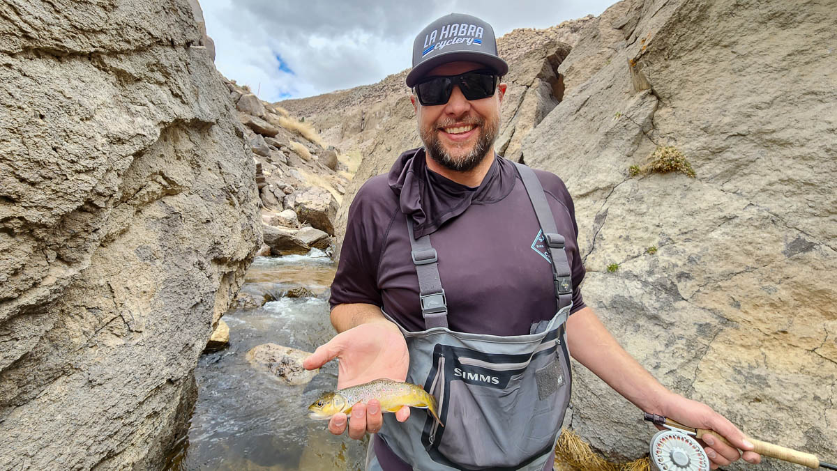 A fly fisherman in the Owens River Gorge with a wild brown trout.