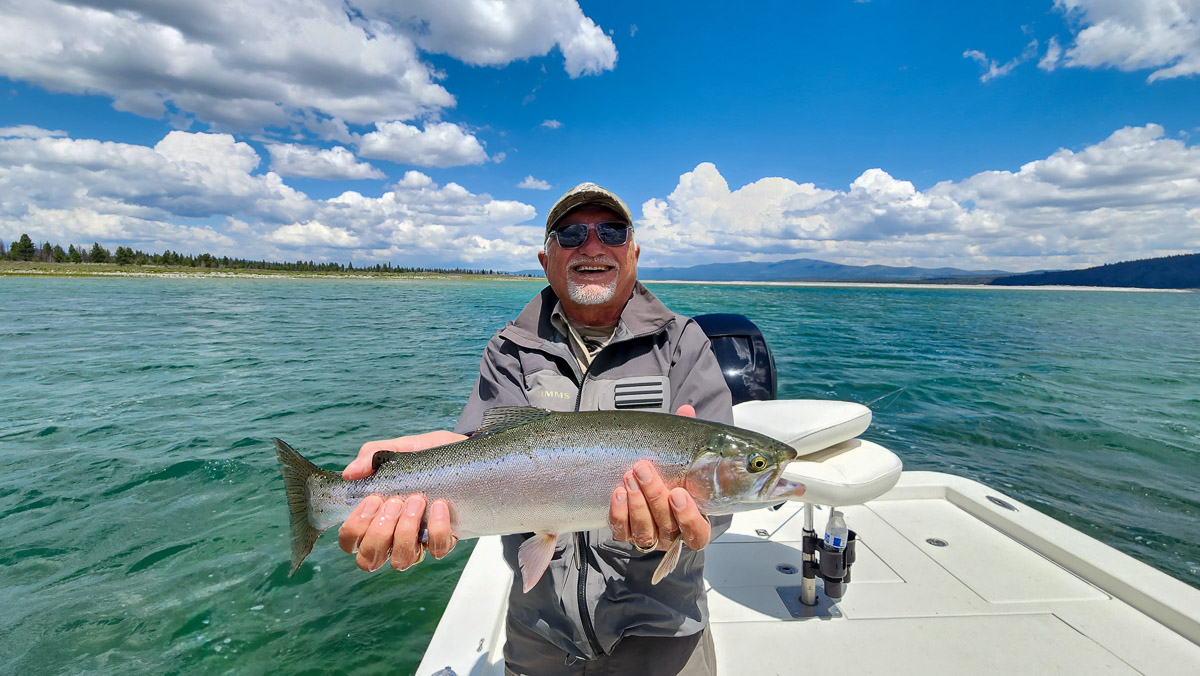 A fisherman holding a large rainbow trout from Eagle Lake on a boat.