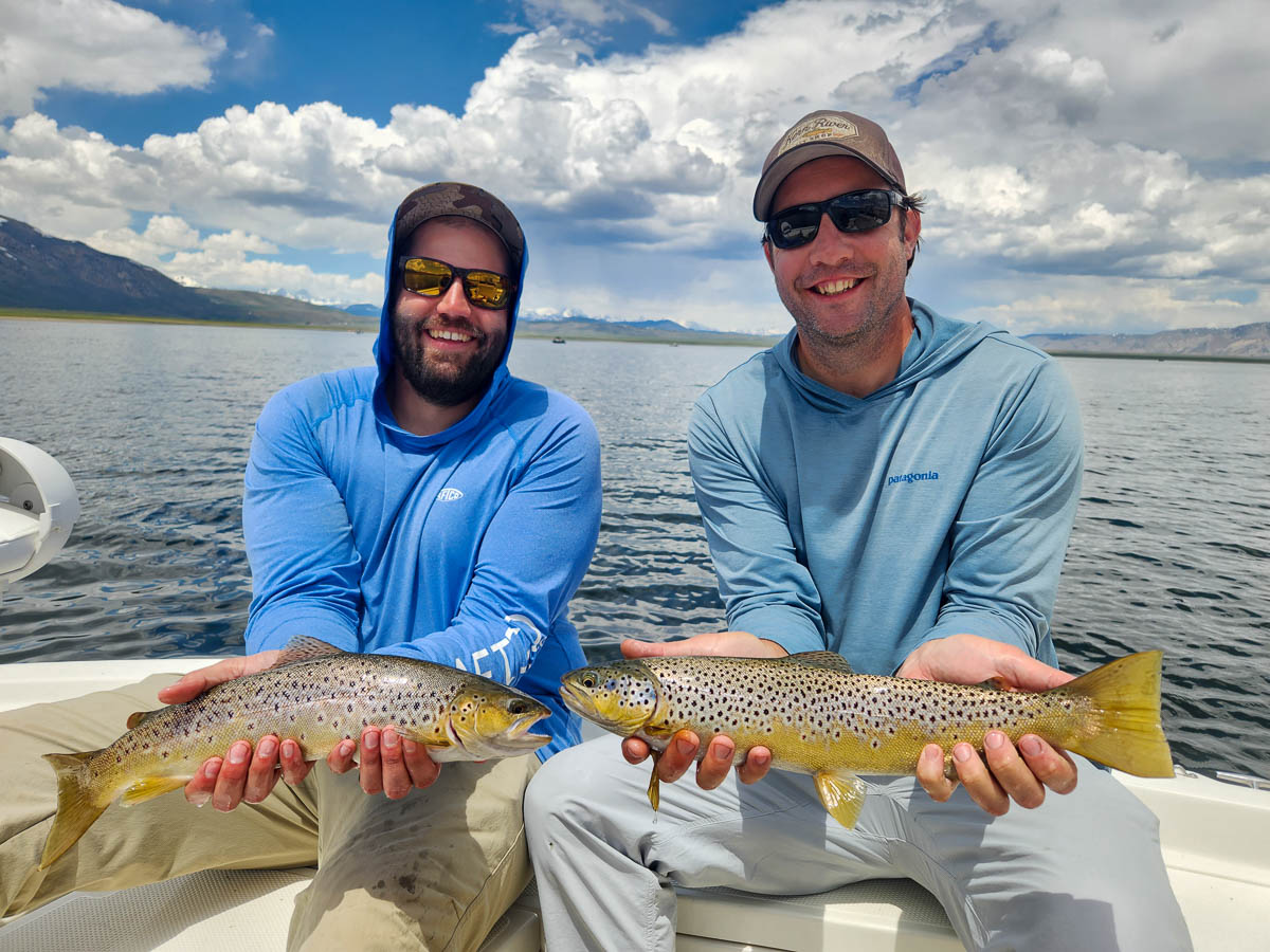 A couple of fisherman holding a pair of large brown trout from Crowley Lake on a boat.