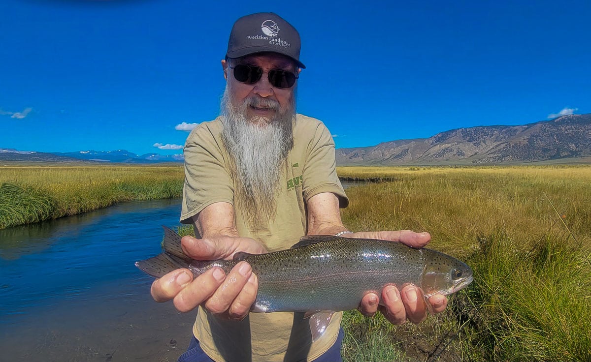 A fisherman holding a large rainbow trout from the Upper Owens River.