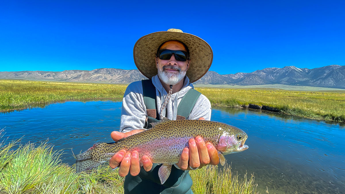 A fisherman holding a large rainbow trout from the Upper Owens River.