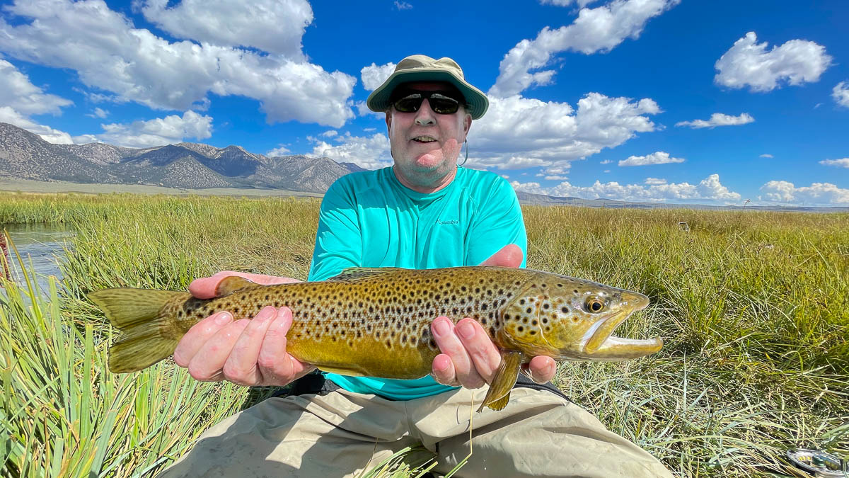 A fisherman holding a large brown trout from the Upper Owens River.