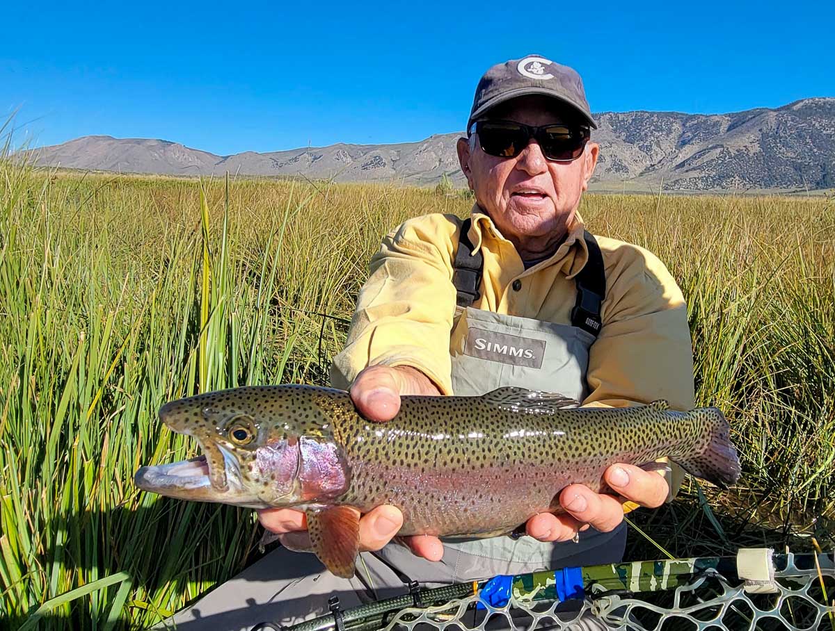A fisherman holding a rainbow trout from the Upper Owens River.