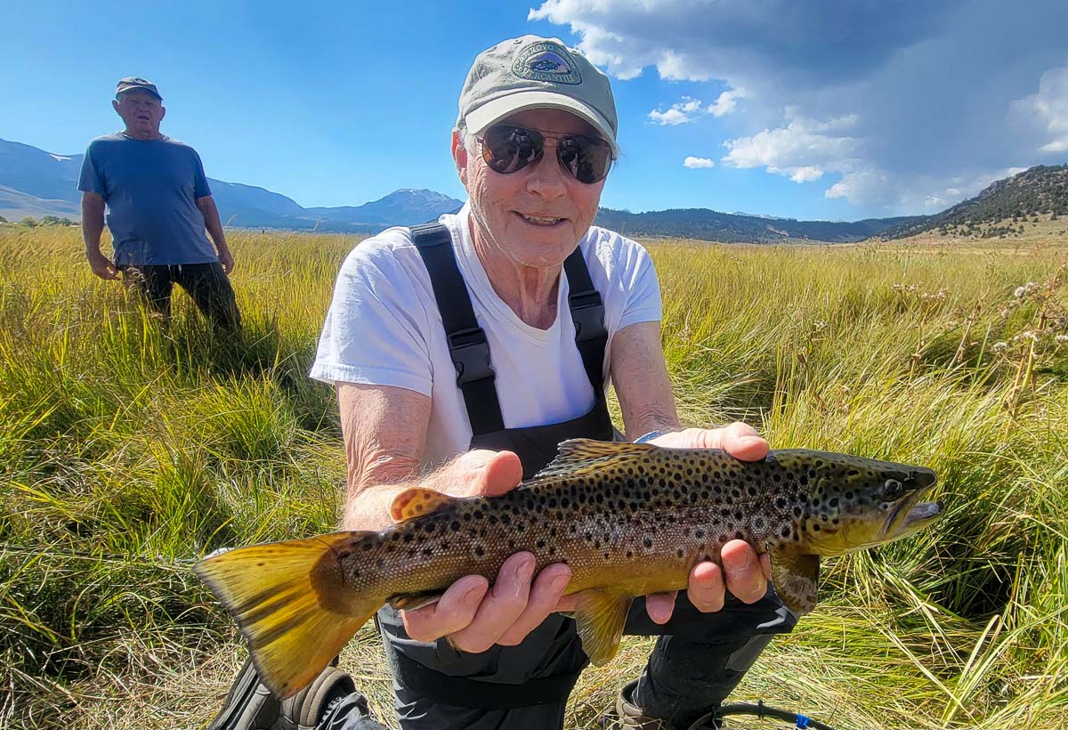 A fisherman holding a large brown trout from the Upper Owens River.