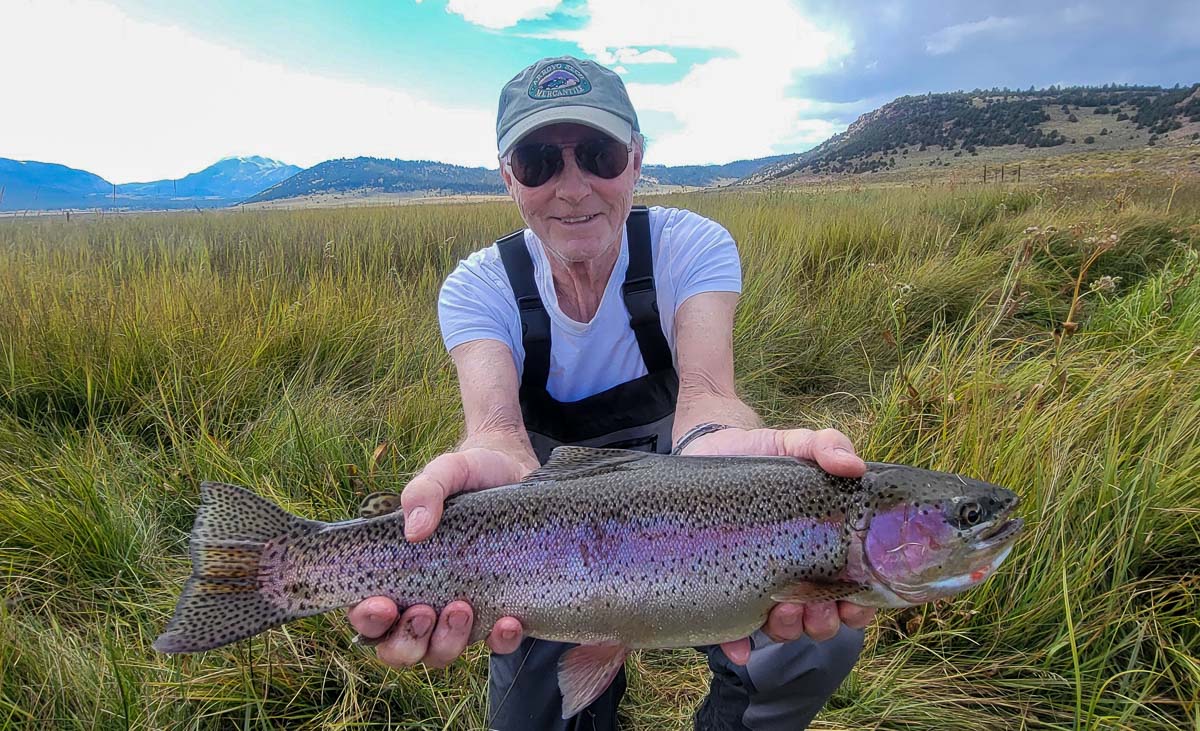 A fisherman holding a large brown trout on the Upper Owens River.