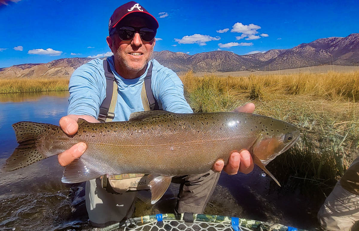 A smiling fisherman holding a large rainbow trout on the Upper Owens River