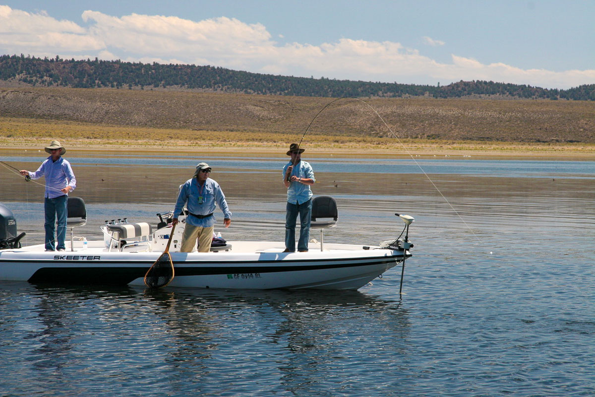 Three men fly fishing from a Skeeter boat on Crowley Lake in California.