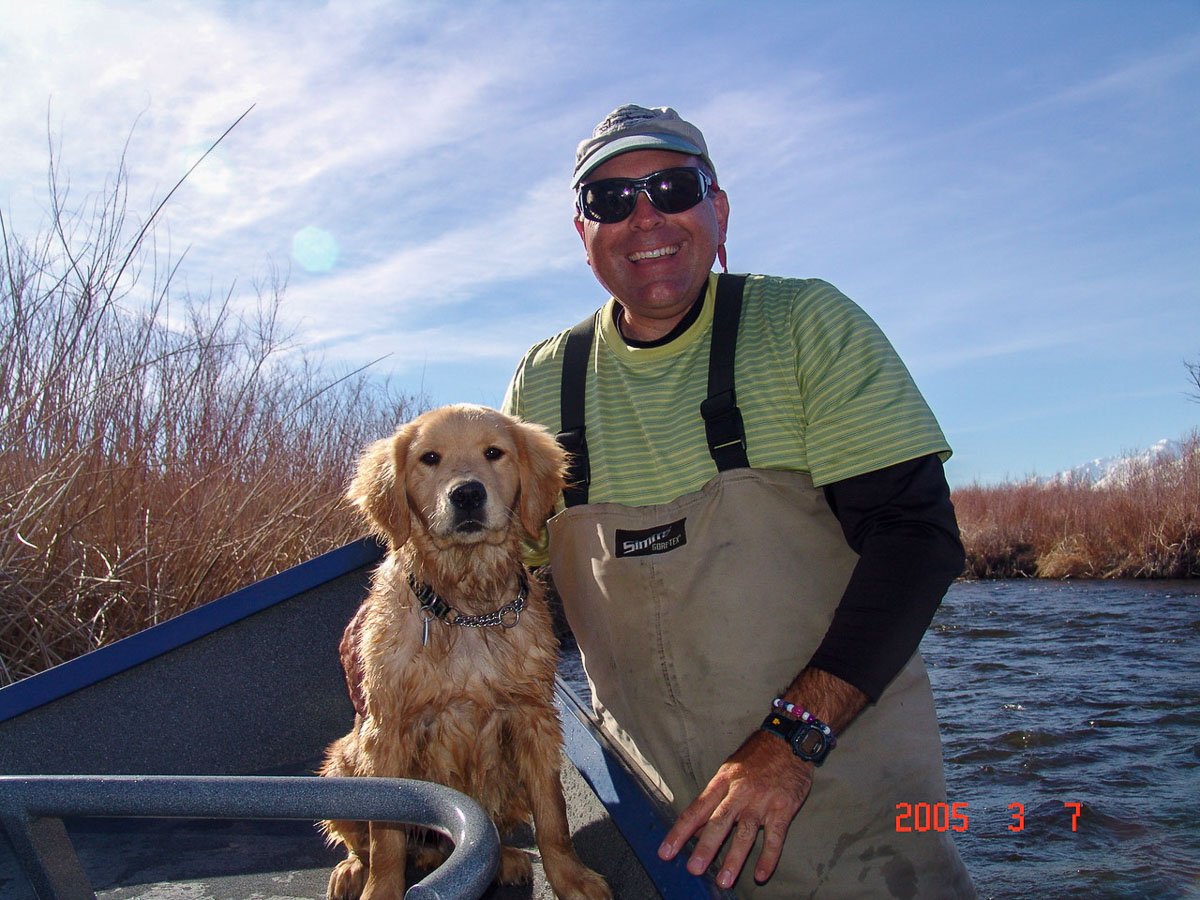 A man in waders and a Golden Retriever in a drift boat on the Lower Owens River.