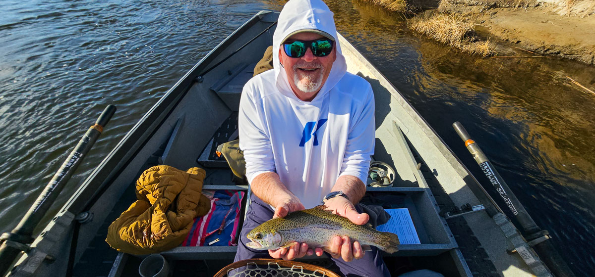 A smiling fisherman holding a rainbow trout on the Lower Owens River.