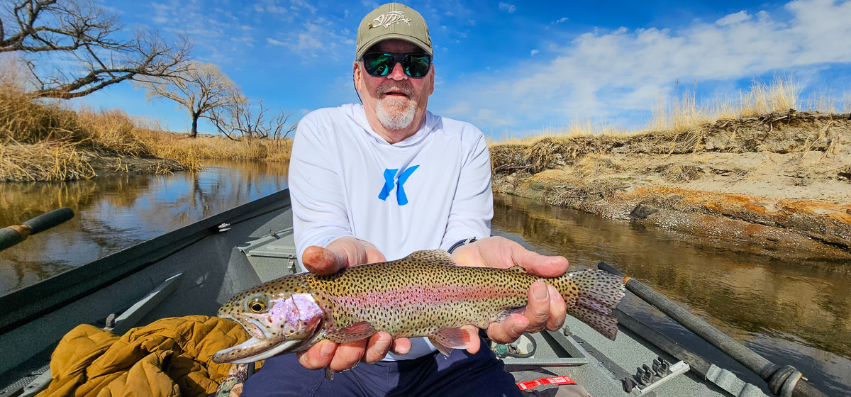 A smiling fisherman holding a large rainbow trout on the Lower Owens River.