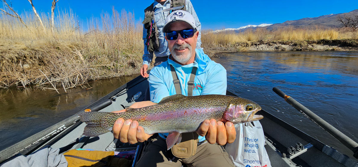A smiling fisherman holding a large rainbow trout on the Lower Owens River.