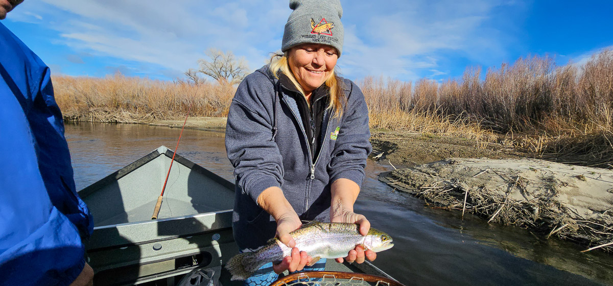 A smiling fisherwoman holding a large rainbow trout on the Lower Owens River.