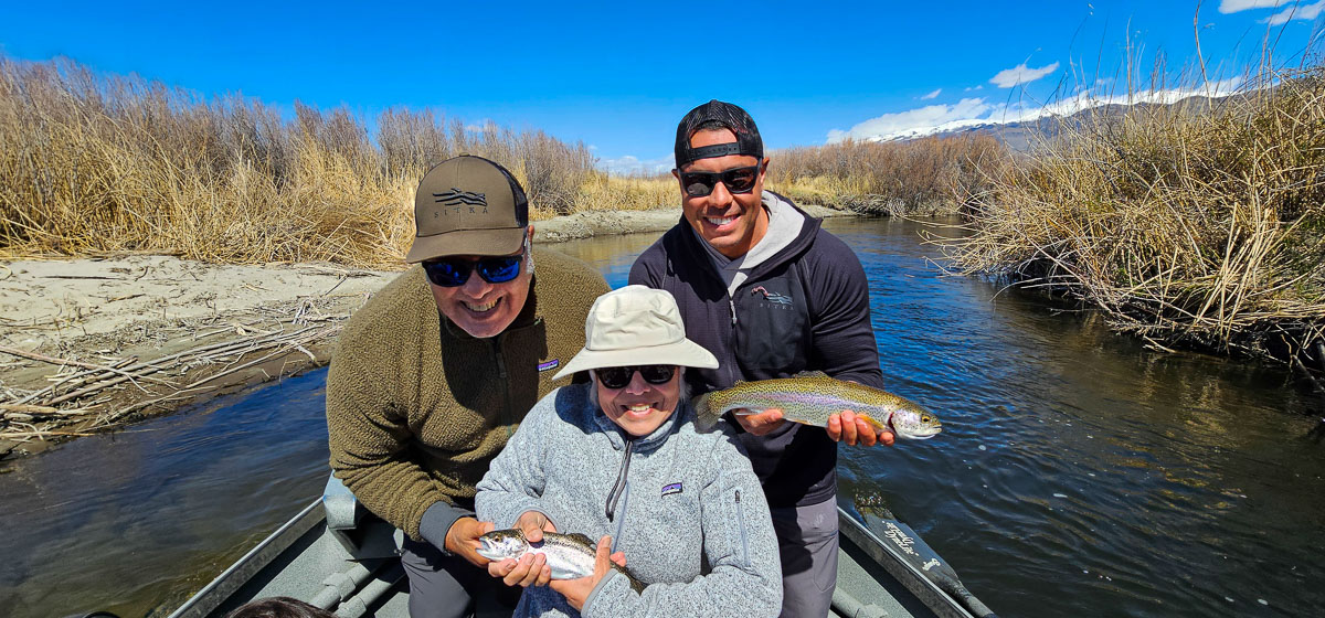 A smiling trio of fisherman holding a couple large rainbow trout on the Lower Owens River.