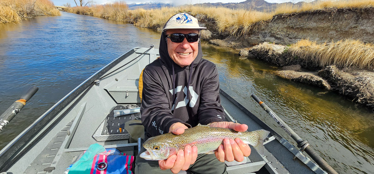 A smiling fisherman holding a rainbow trout on the Lower Owens River.