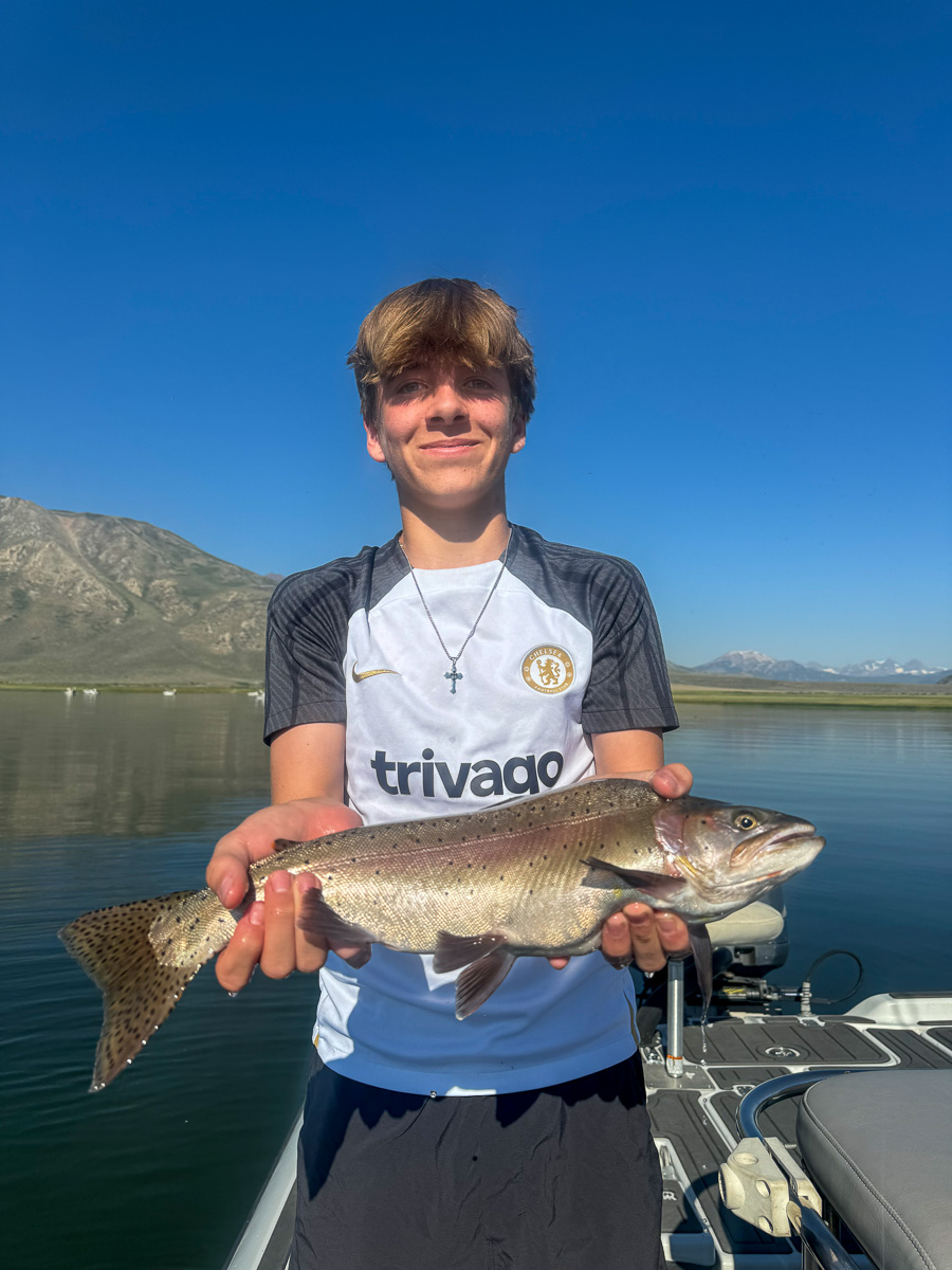 A fly fishermen holding a larger rainbow trout in a boat on Crowley Lake in the Eastern Sierra.