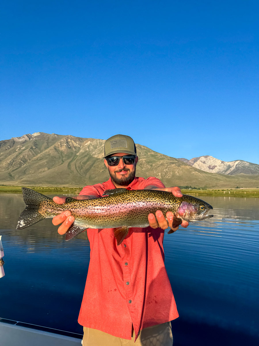 A fly fishermen holding a larger rainbow trout in a boat on Crowley Lake in the Eastern Sierra.