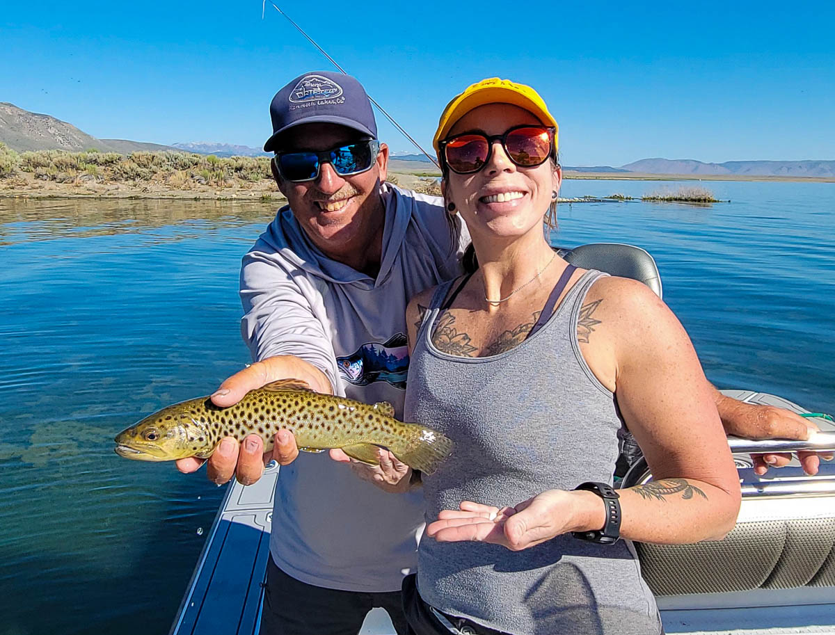 A fly fishermen holding a larger rainbow trout in a boat on Crowley Lake in the Eastern Sierra.