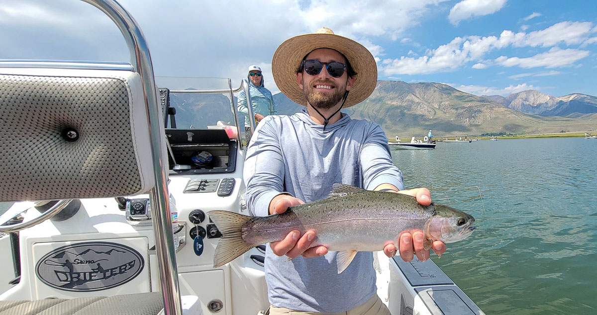 A fly fishermen holding a larger rainbow trout in a boat on Crowley Lake in the Eastern Sierra.