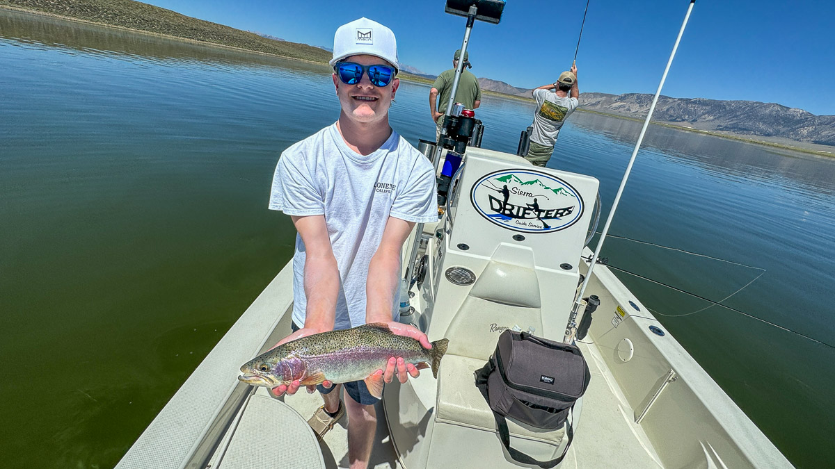 A fly fishermen holding a large rainbow trout in a boat on Crowley Lake in the Eastern Sierra.