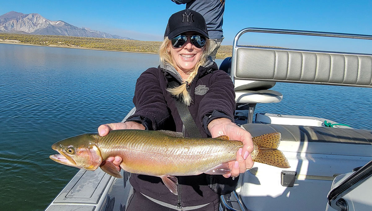 A fly fishermen holding a large rainbow trout in a boat on Crowley Lake in the Eastern Sierra.