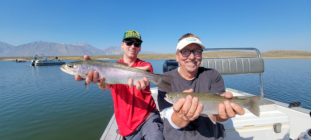 A fly fishermen holding a large rainbow trout in a boat on Crowley Lake in the Eastern Sierra.