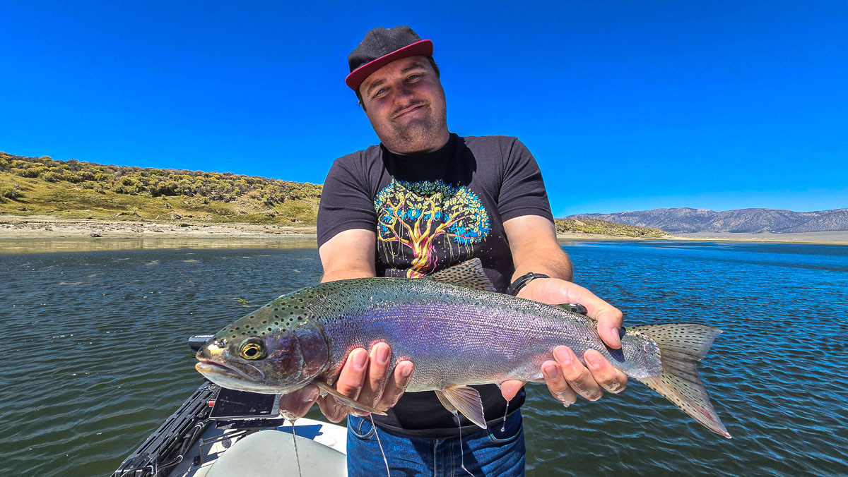 A fly fishermen holding a large cutthroat trout in a boat on Crowley Lake in the Eastern Sierra.