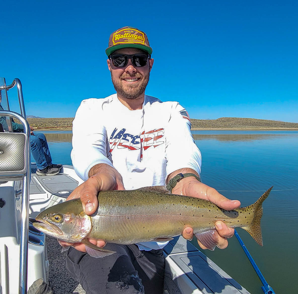 A fly fishermen holding a large rainbow trout in a boat on Crowley Lake in the Eastern Sierra.